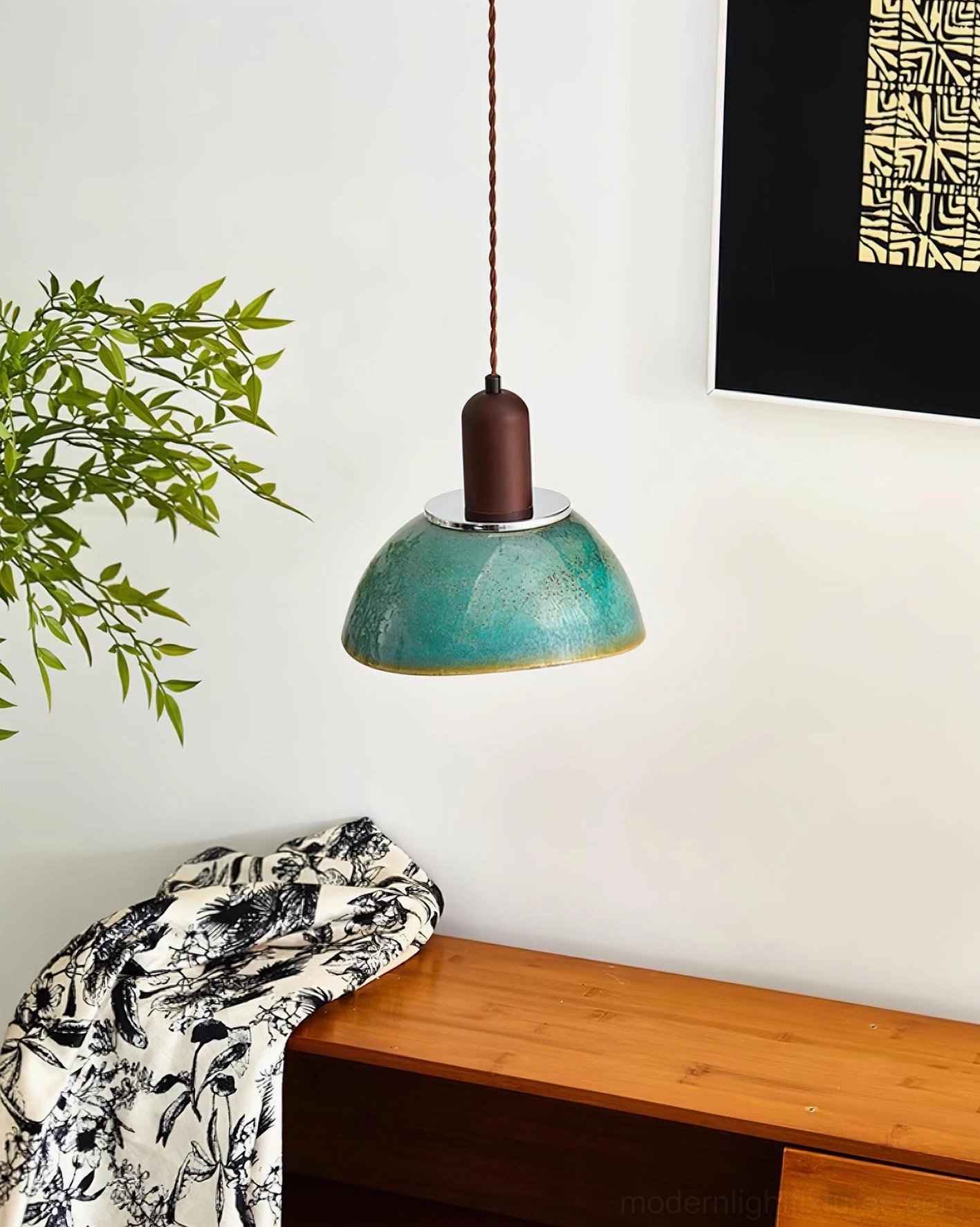 Teal ceramic pendant lamp side angle view in contemporary home corner with green plant and wooden console furniture