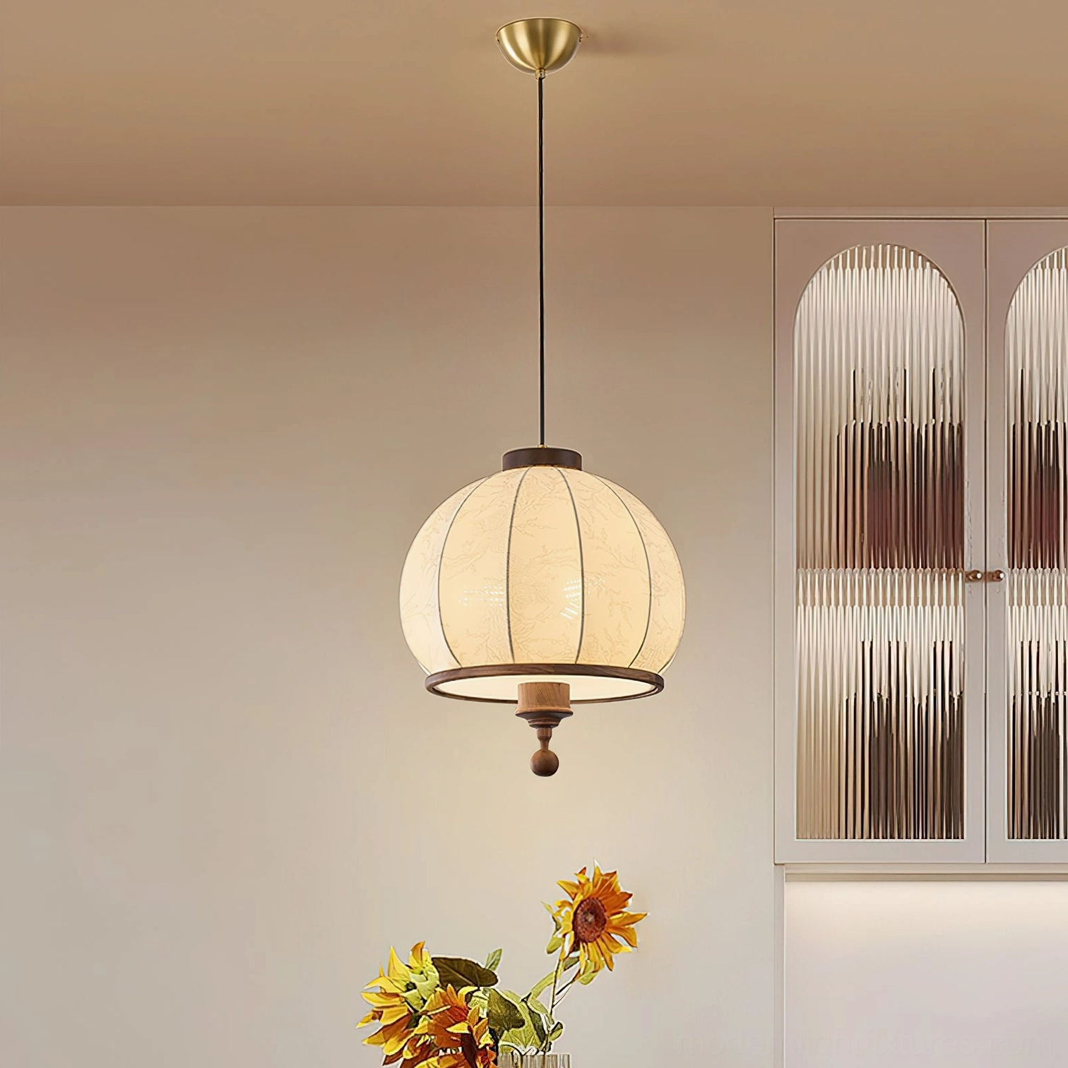Round fabric pendant light suspended above dining area with glass cabinet and warm ambient lighting