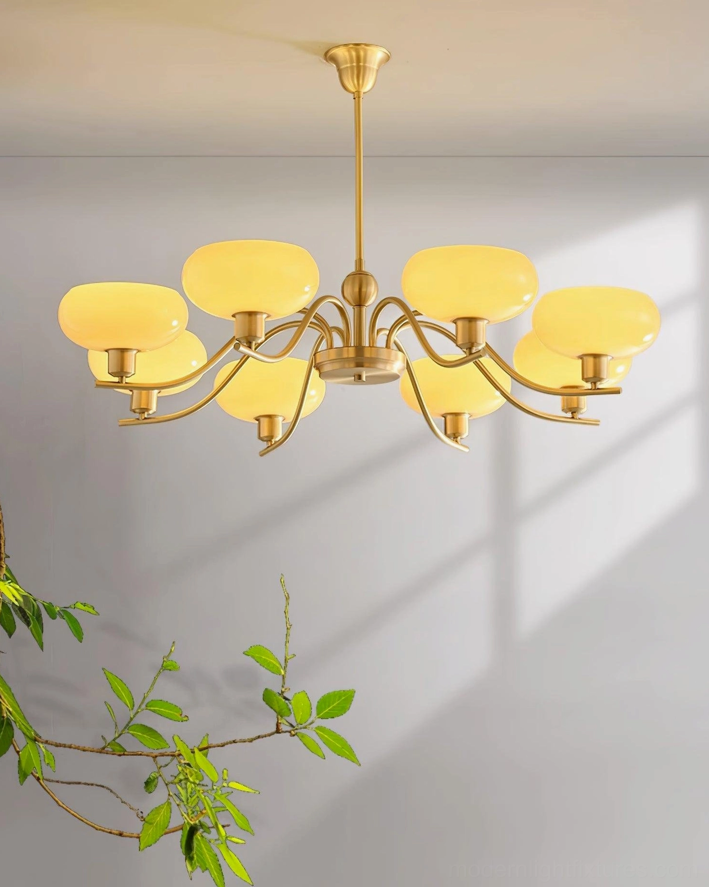 Havana 8-head brass pendant chandelier with warm beige glass shades on green foliage studio background