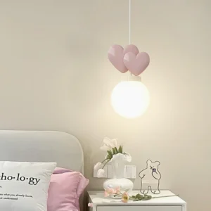 Modern heart pendant light in bedroom with grey upholstered headboard creating warm ambient lighting