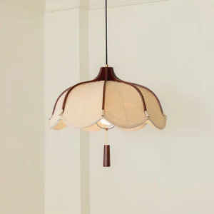 Close-up detail of Helia pendant lamp showing scalloped linen shade with dark wood trim and decorative pull tab