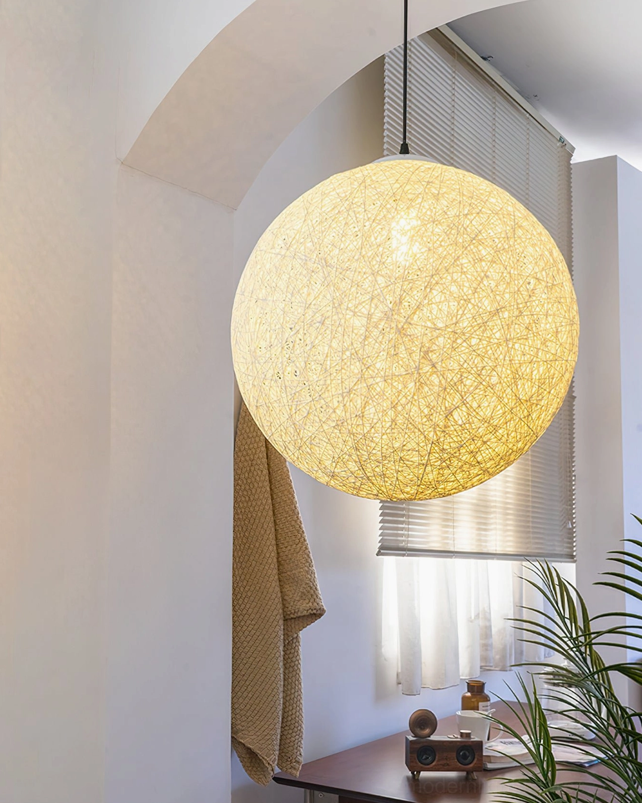 Hemp sphere ceiling pendant light side view in home office space with desk, green plant, natural daylight from side window