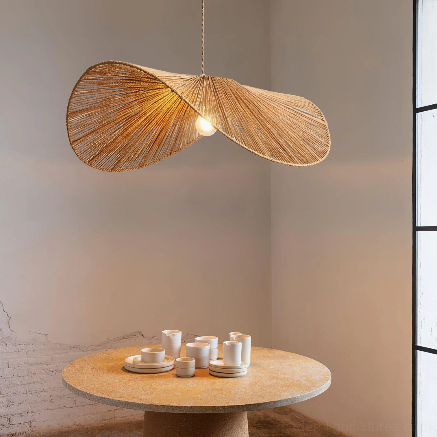 Woven straw hat style pendant light suspended above round wooden dining table in modern residential interior