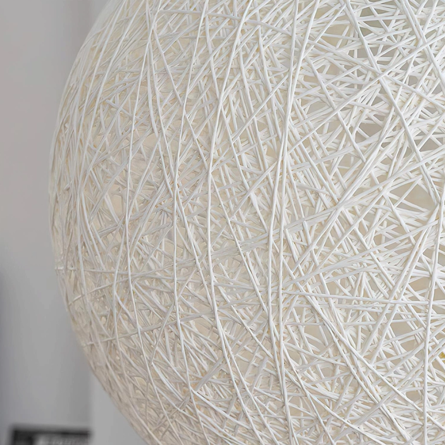 Handwoven hemp sphere pendant light in bohemian style interior with natural textiles and rustic decor elements