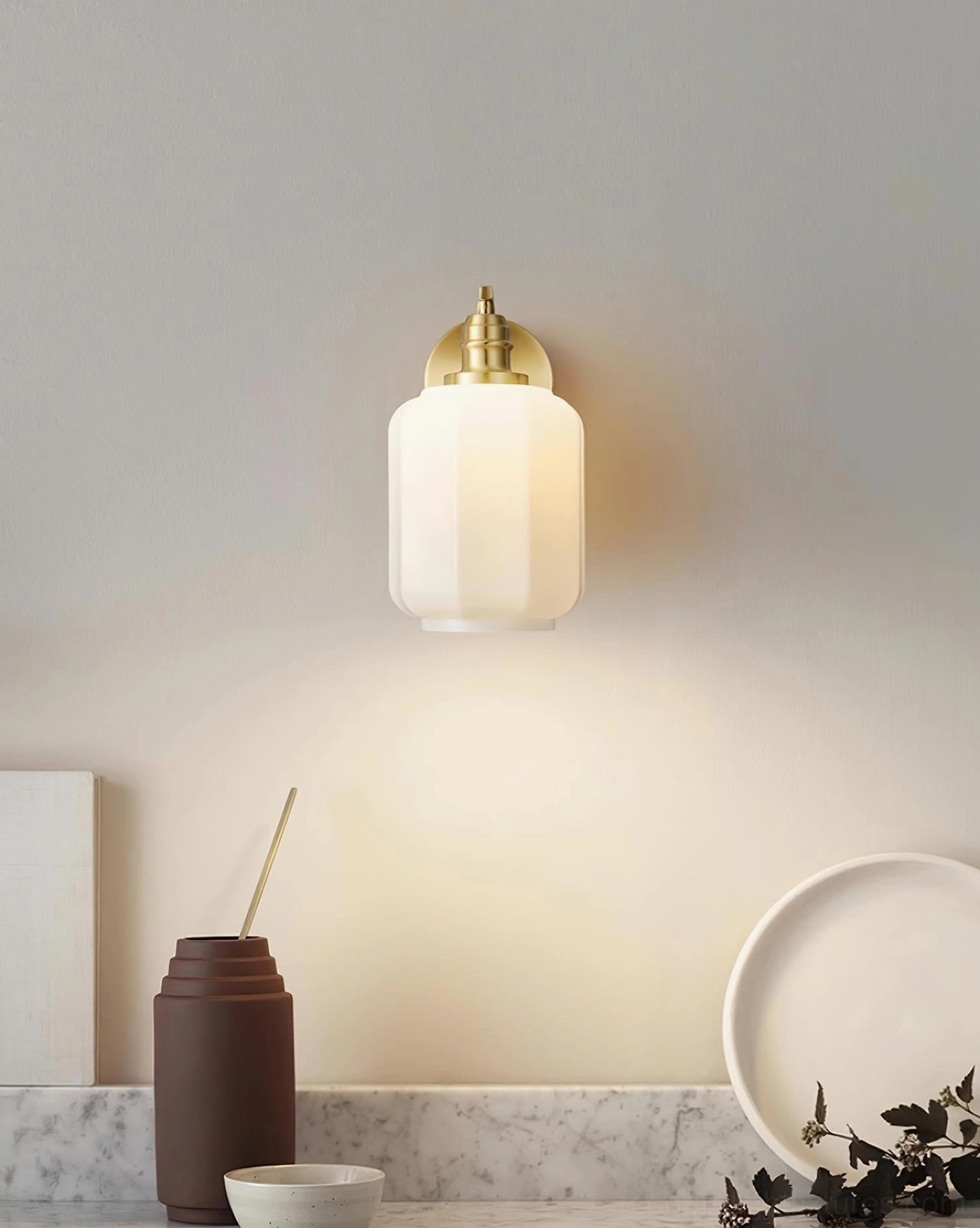 Henry brass wall sconce installed in living room with eclectic modern art and green plant decor