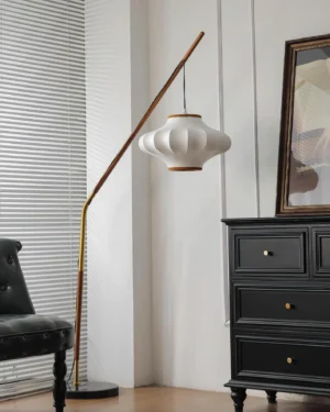 Modern arc floor lamp with brass accents and warm-toned pleated fabric shade in vintage living room setting