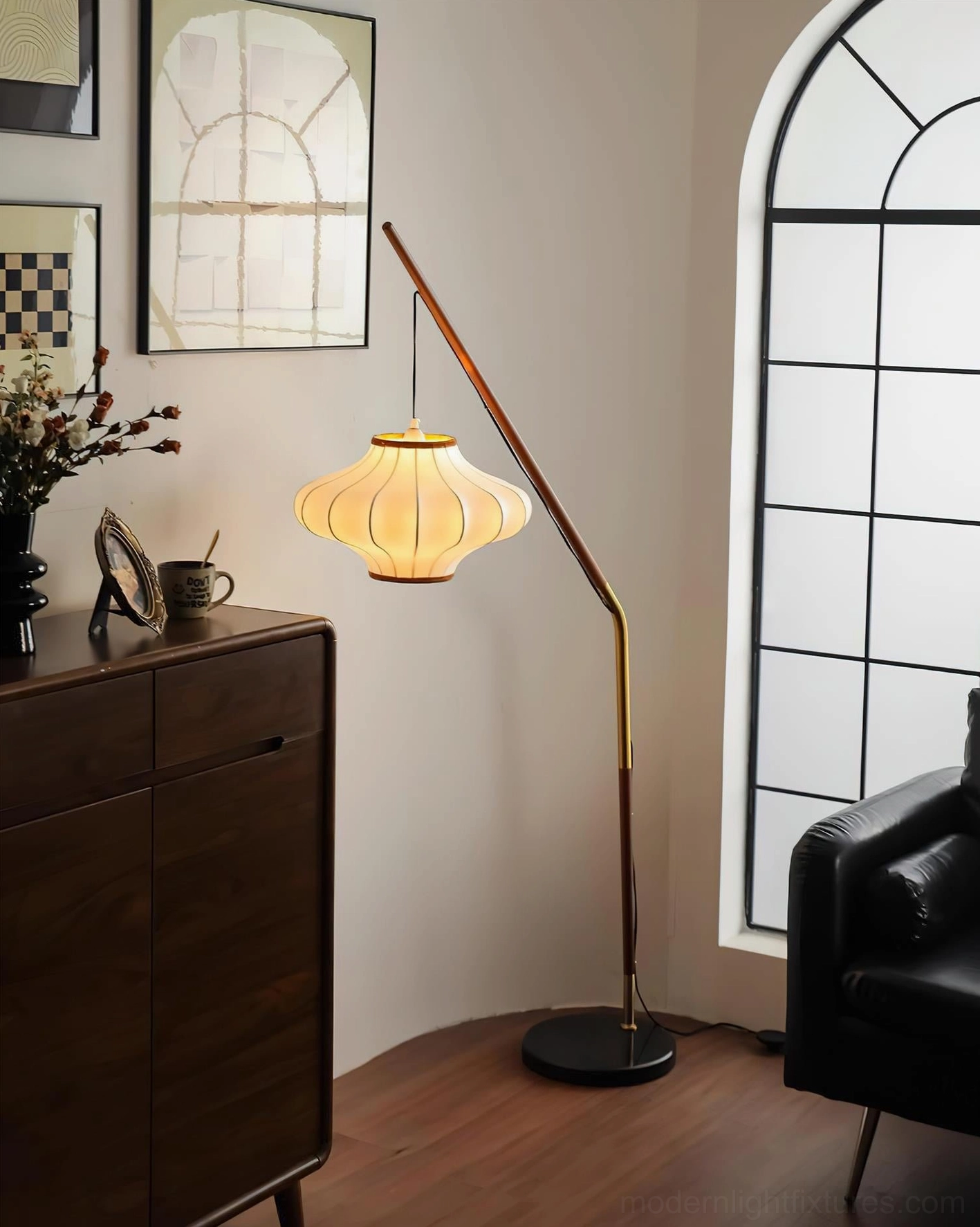 Hikari arc floor lamp illuminated with warm glow casting soft ambient light in modern minimalist room