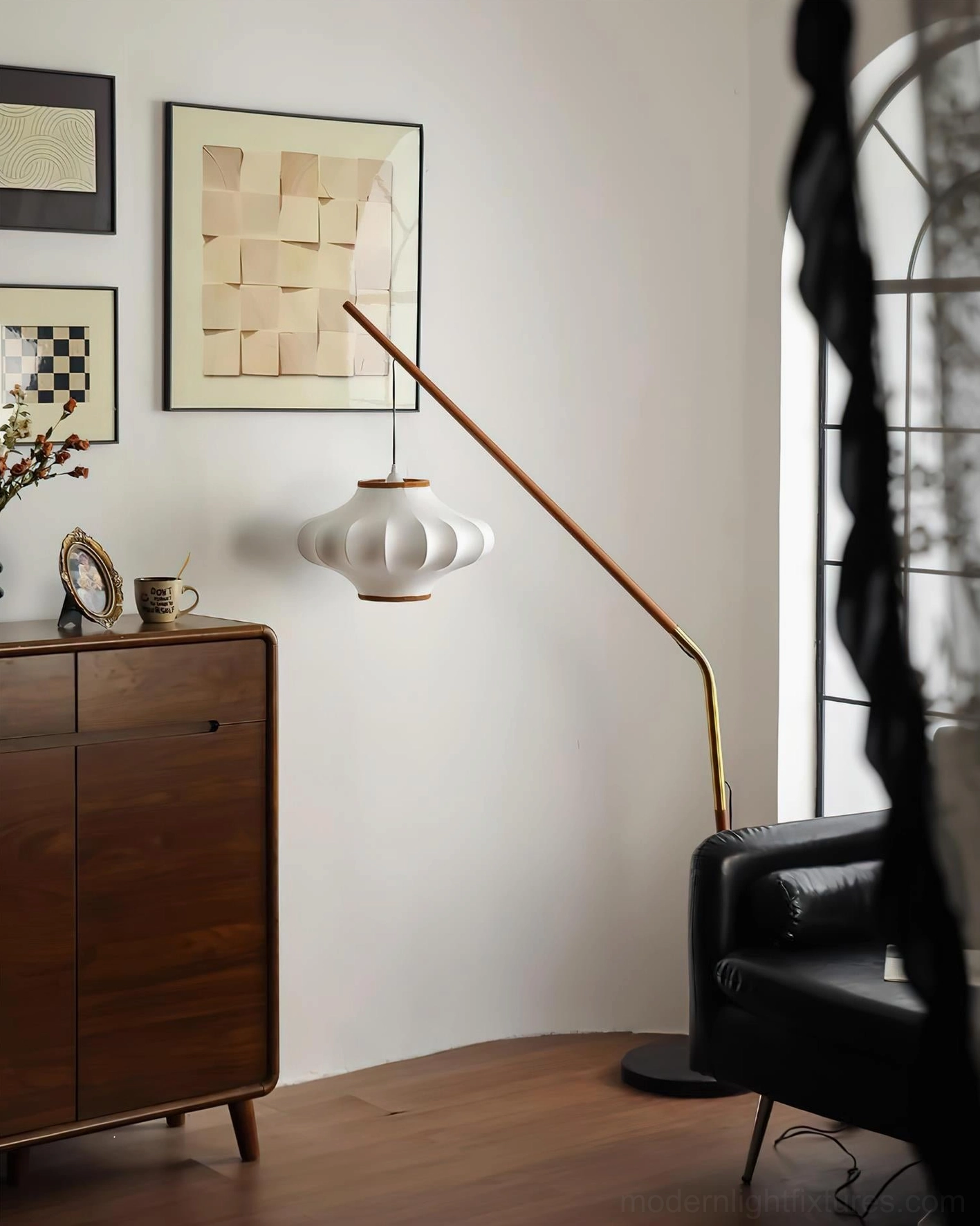 Unlit arc floor lamp with sculptural design, white pleated shade, and walnut wooden pole in modern living room
