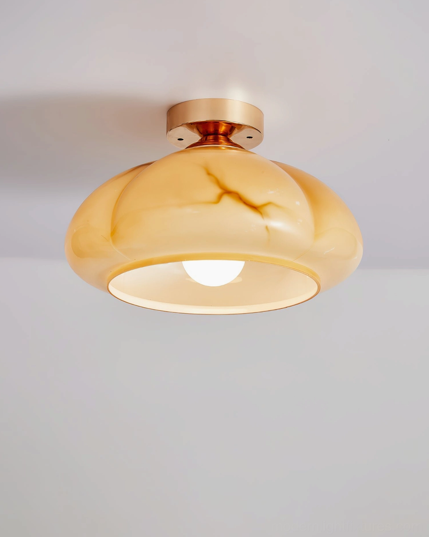 Illuminated marbled amber glass ceiling light fixture showing warm internal bulb glow and smooth glass finish