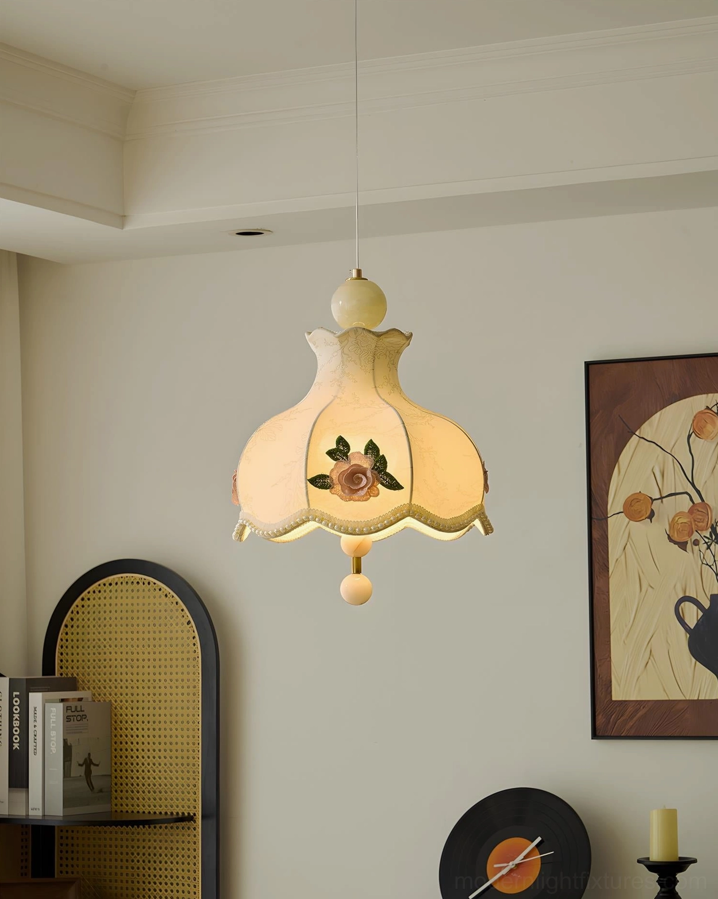 Illuminated embroidered floral pendant light glowing with warm yellow light in interior with beige walls and rattan shelf