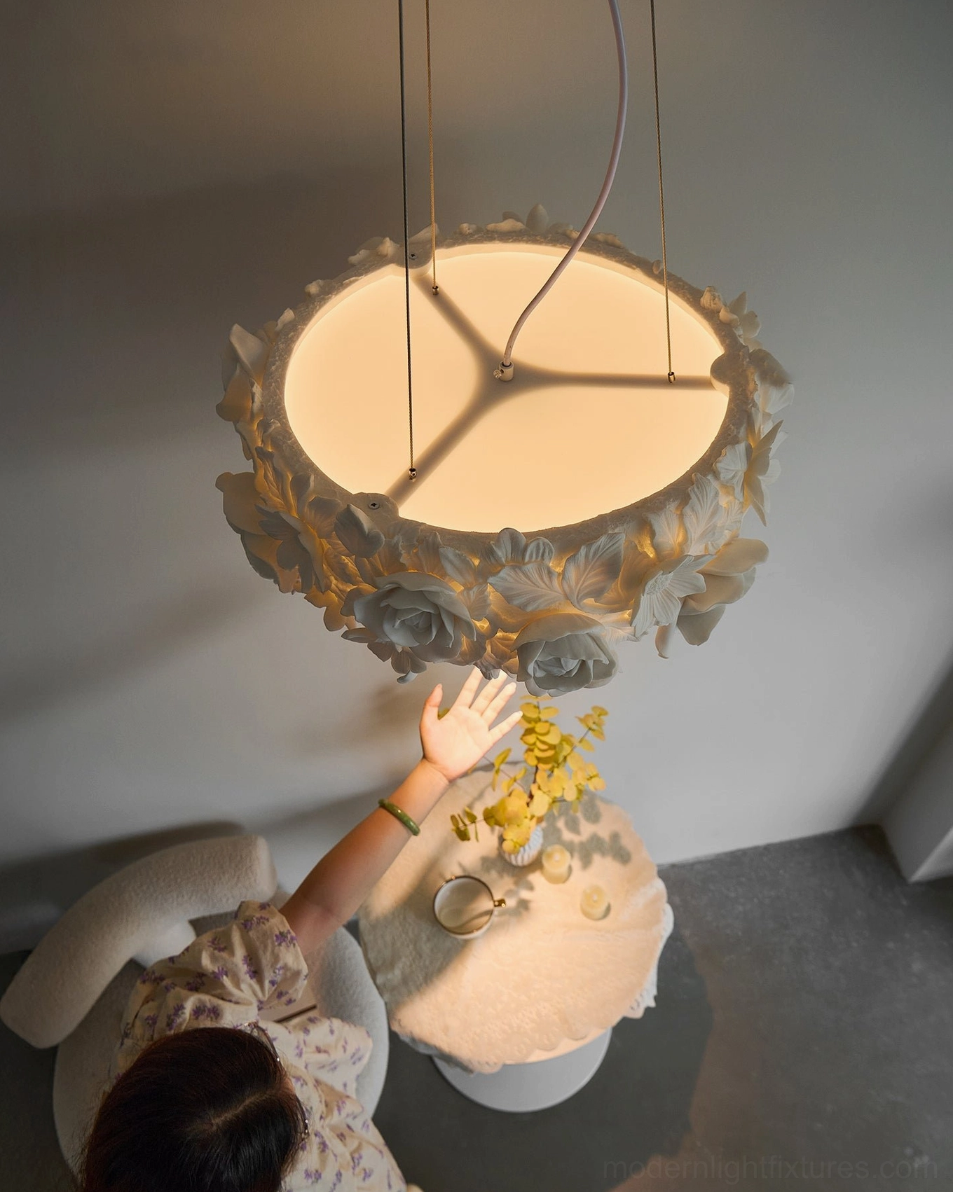 Illuminated handcrafted ceramic floral pendant lamp with warm glow, showing dimensional petals and leaf elements