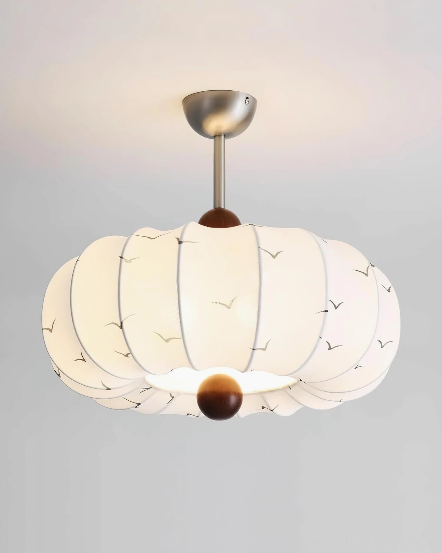 Bird Song fabric pendant light illuminated - front view with warm yellow light, showing detailed seagull print pattern and glowing diffusion