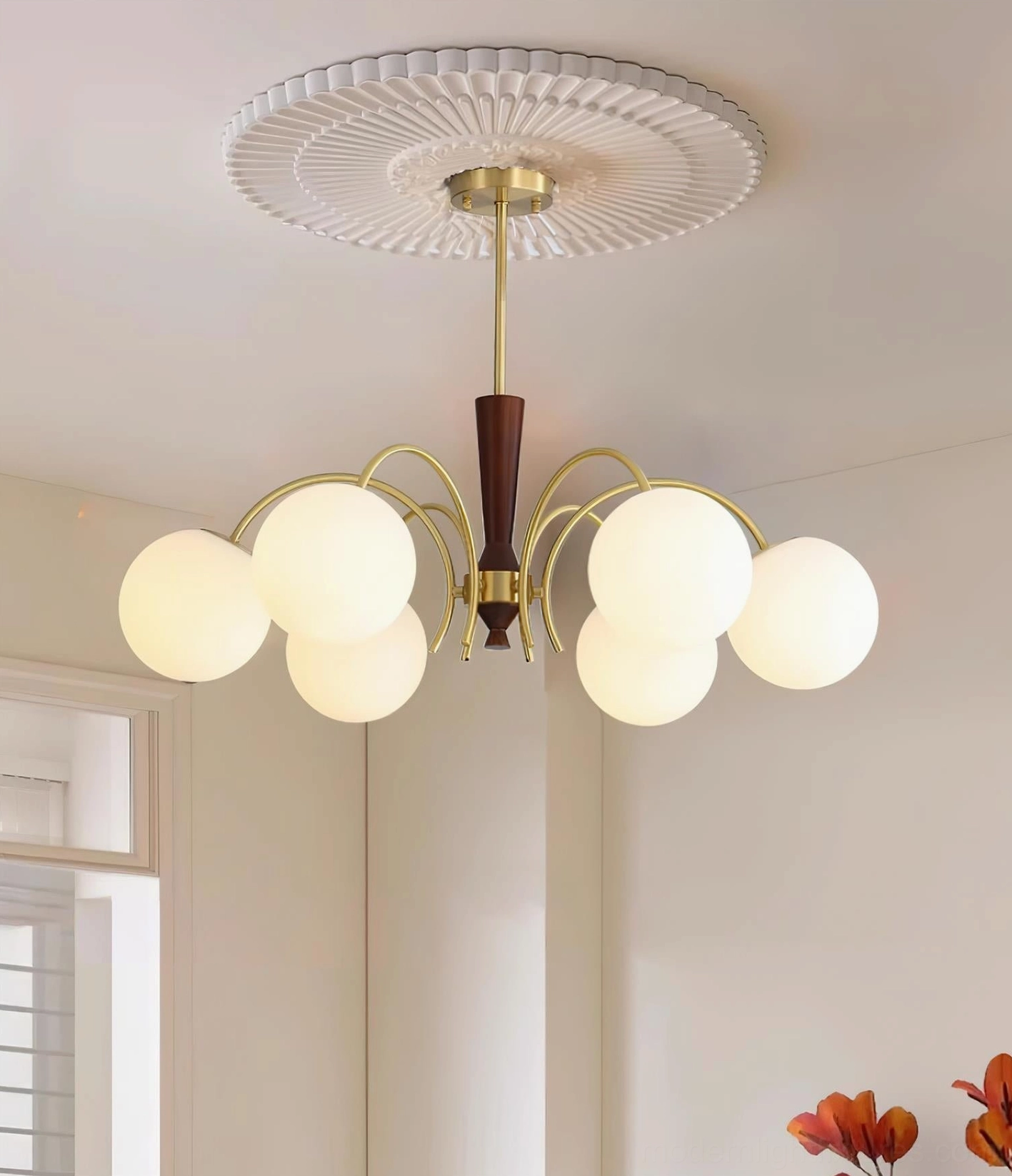 Lit globe chandelier installed in residential interior with warm ambient lighting and decorative ceiling trim