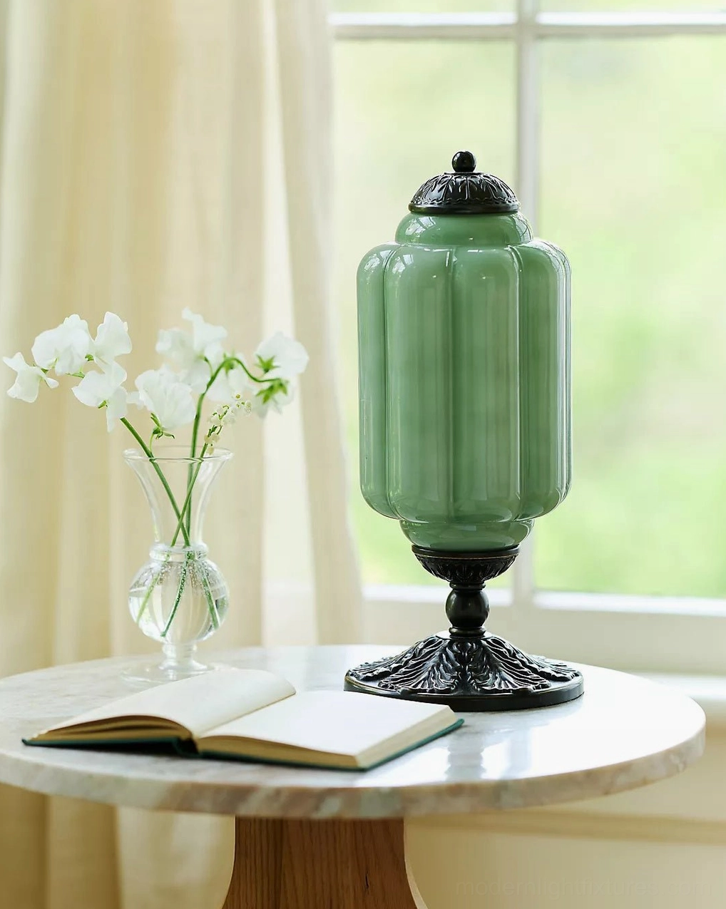 Jade green fluted glass table lamp with black bronze base on sunlit window side table with flowers and books
