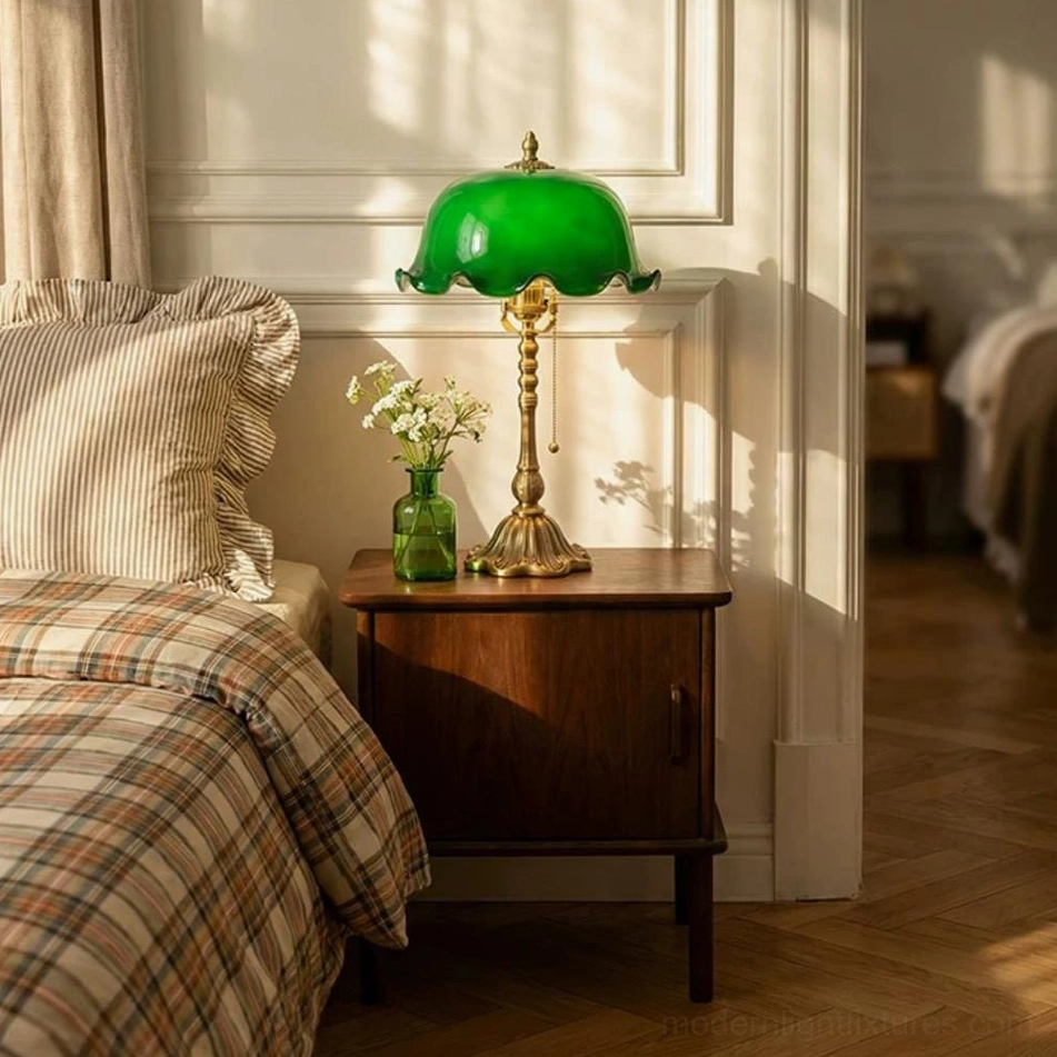 Jadelle green glass table lamp on dark wood nightstand with small floral vase and linen bedding