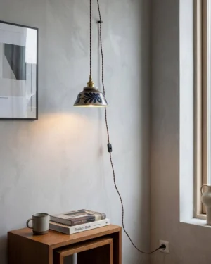 Japandi plug-in pendant light with indigo hand-glazed ceramic shade installed in minimalist residential corner nook, eye-level view