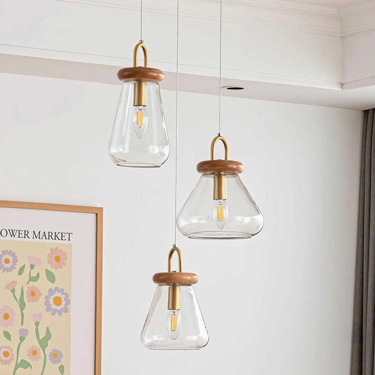 Three-tier jar pendant lights installed at varying heights in minimalist living room with Nordic wall art