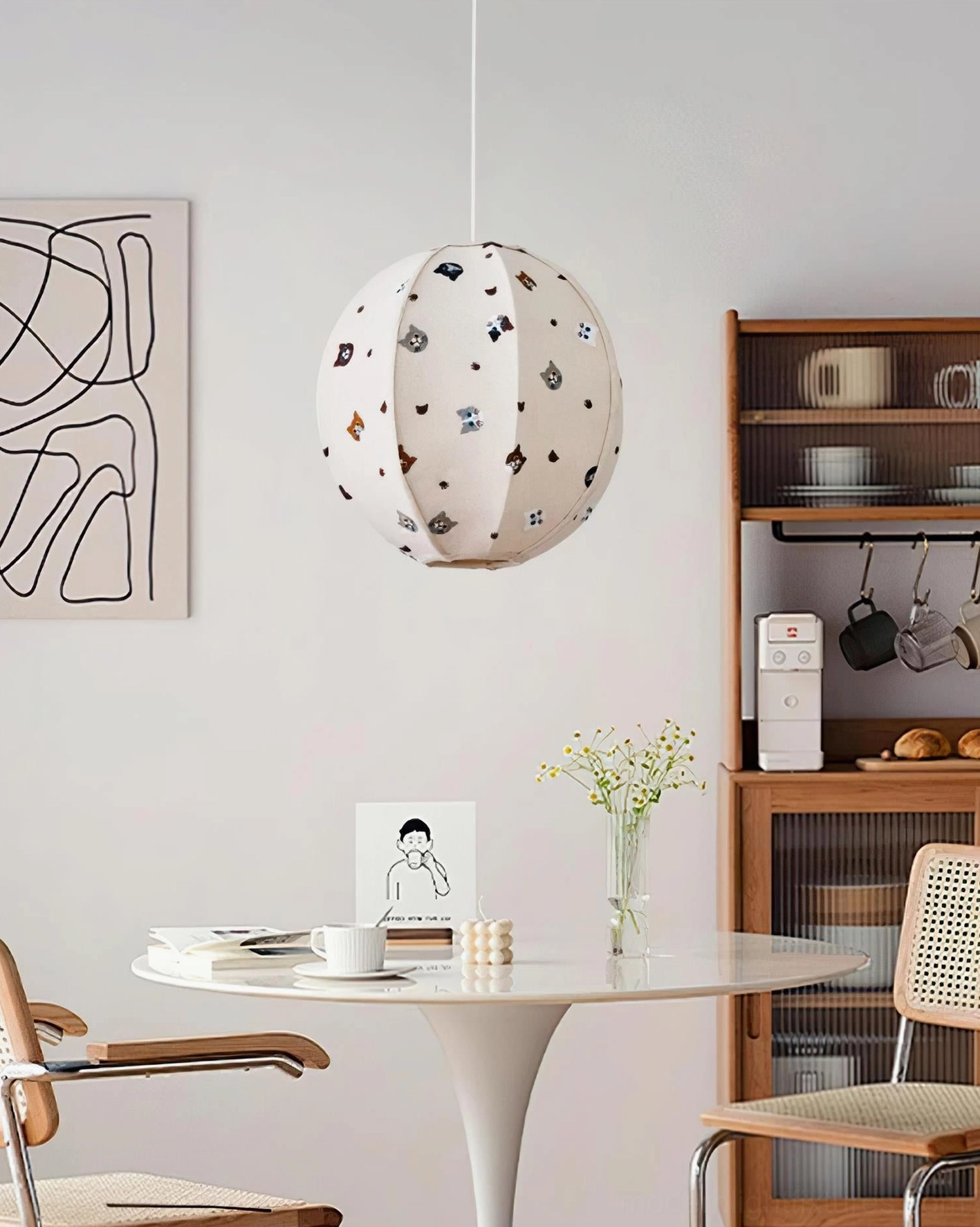 Modern dining room with Jayne cat-patterned pendant light glowing above round table, clean Nordic interior