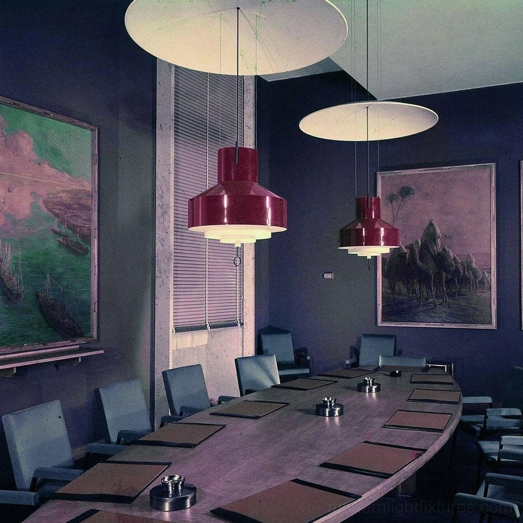 Red adjustable disc pendant lights in corporate conference room with dark walls