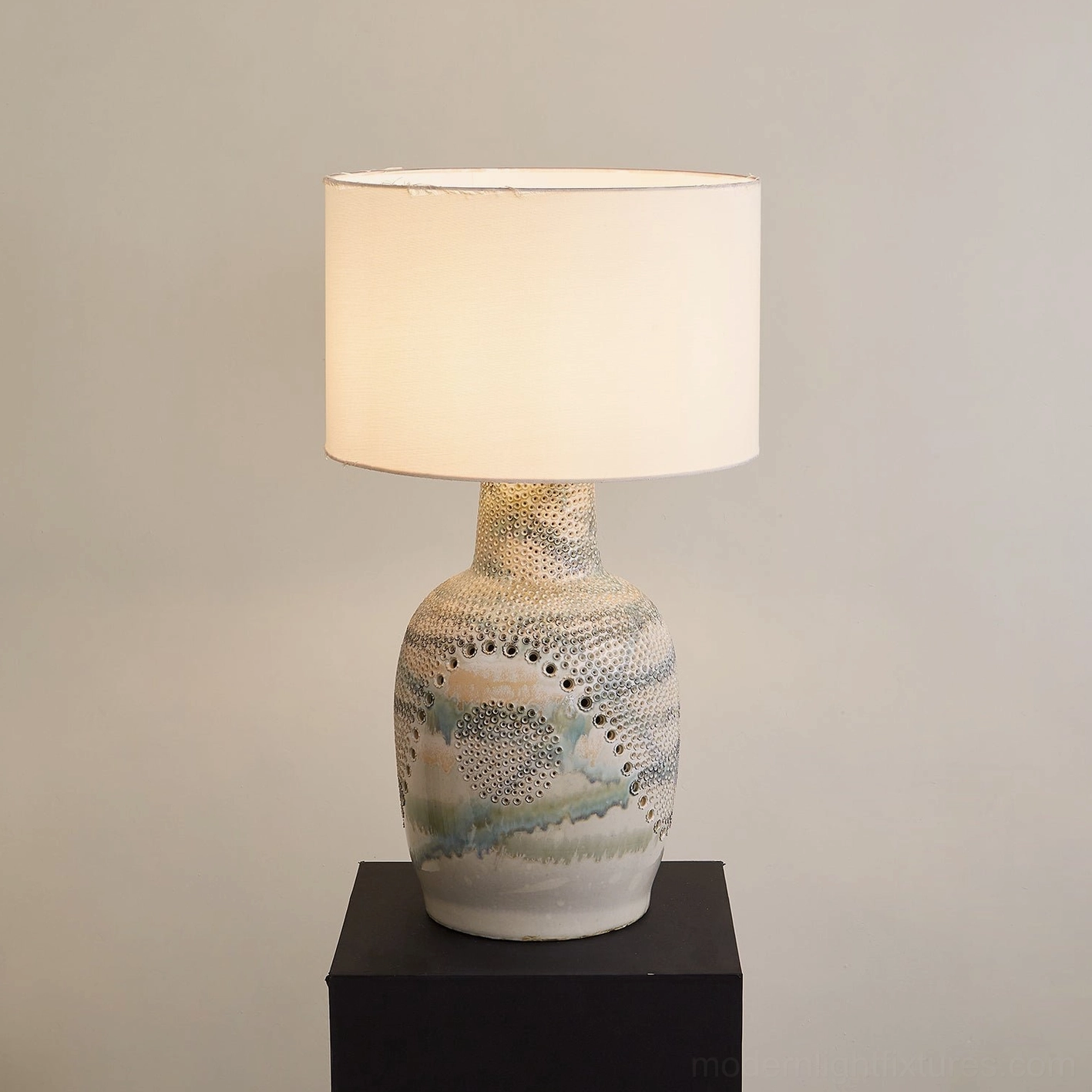 Illuminated Jordyn ceramic table lamp with cream base, detailed glaze and embossed dot pattern, warm lighting
