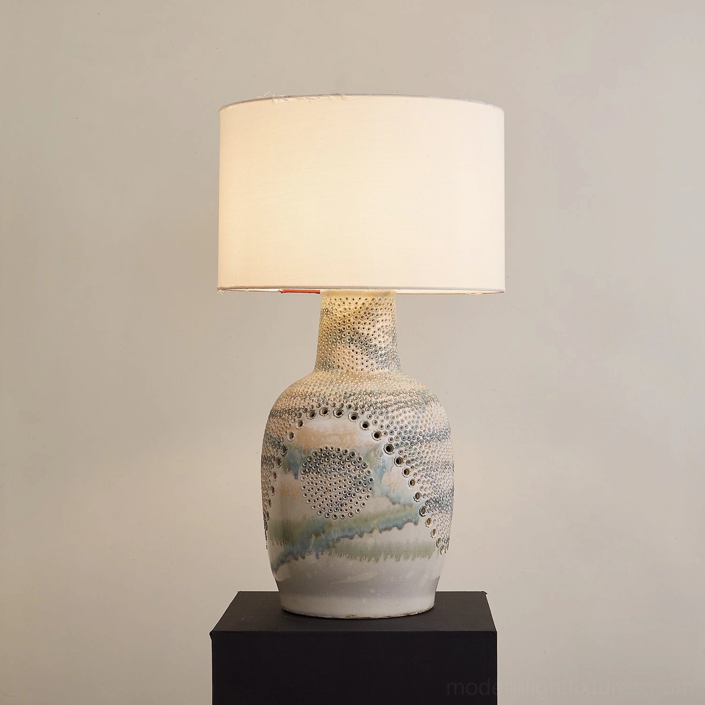 Illuminated Jordyn table lamp with cream and blue-green watercolor glazed ceramic base, lit drum shade
