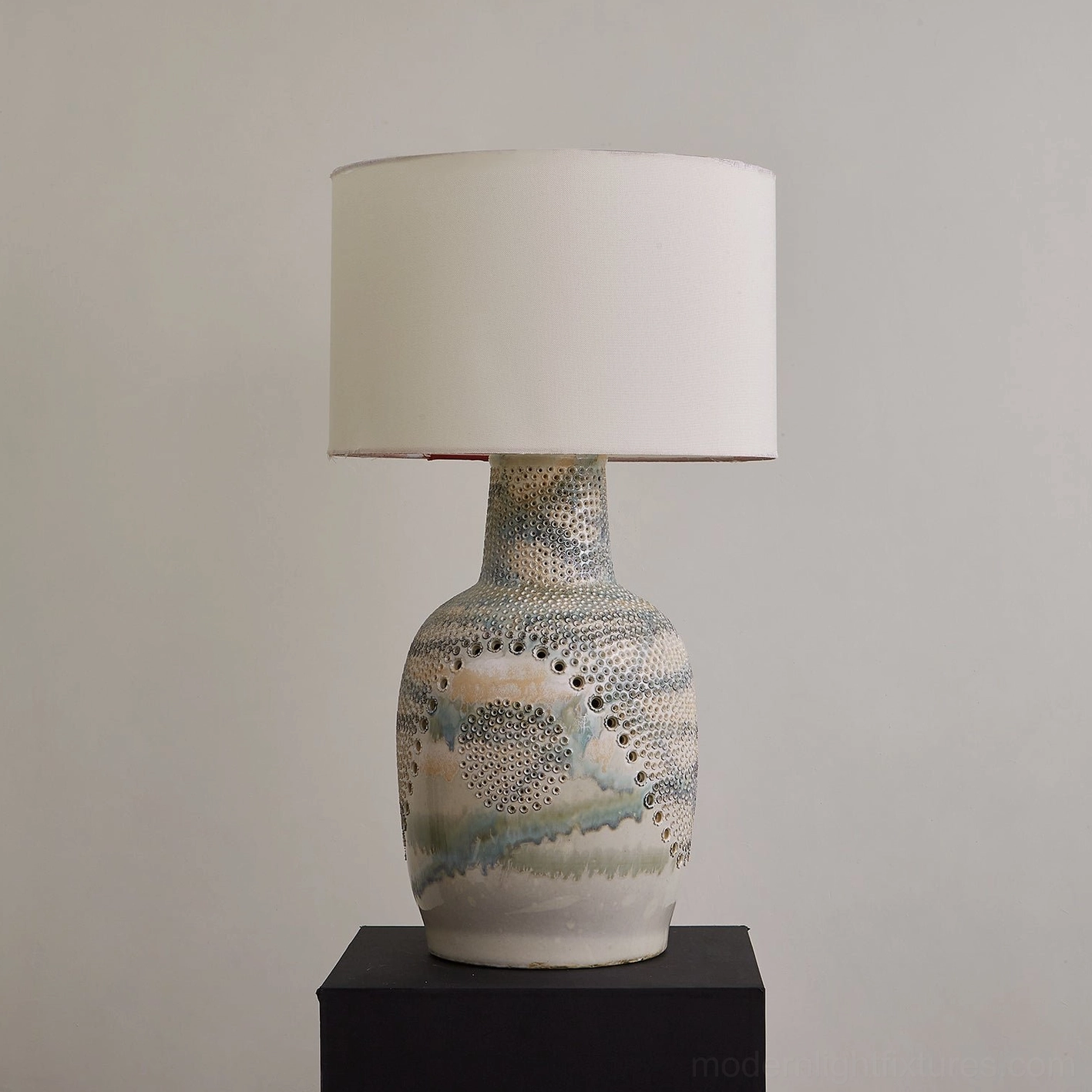 Seafoam sand Jordyn ceramic table lamp with watercolor glaze and hand-embossed dots, unlit on black plinth