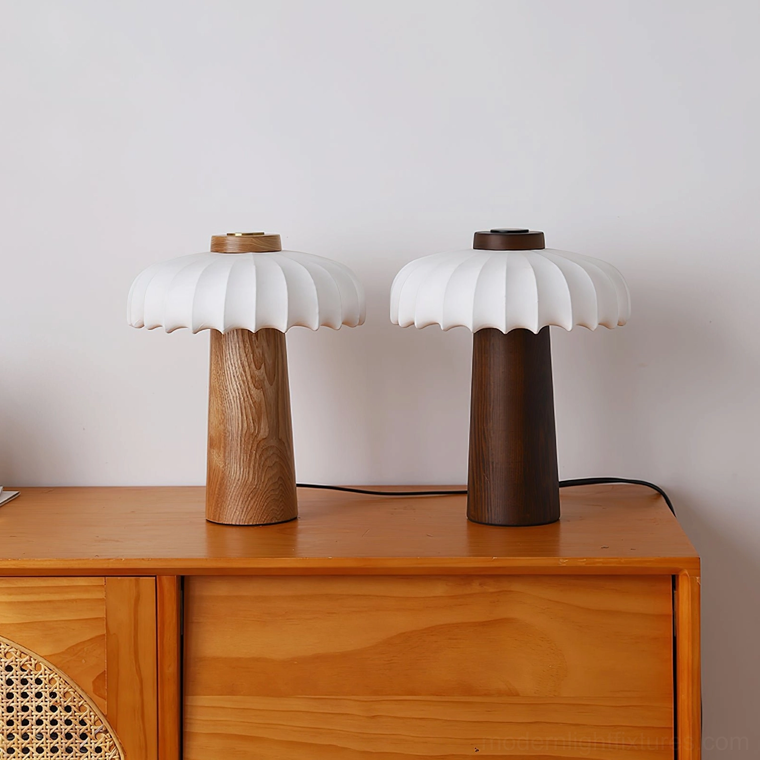 Pair of matching Juego mushroom table lamps with light and dark wood finishes on rattan dresser