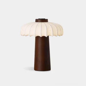 Juego mushroom table lamp with dark brown wood base and pleated fabric shade on white background, front view