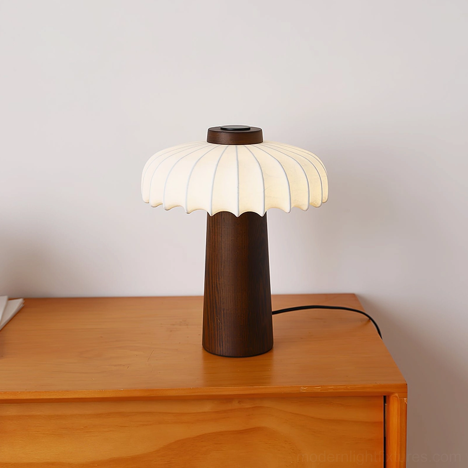 Juego wood base table lamp on dresser with beige fabric shade and minimalist design