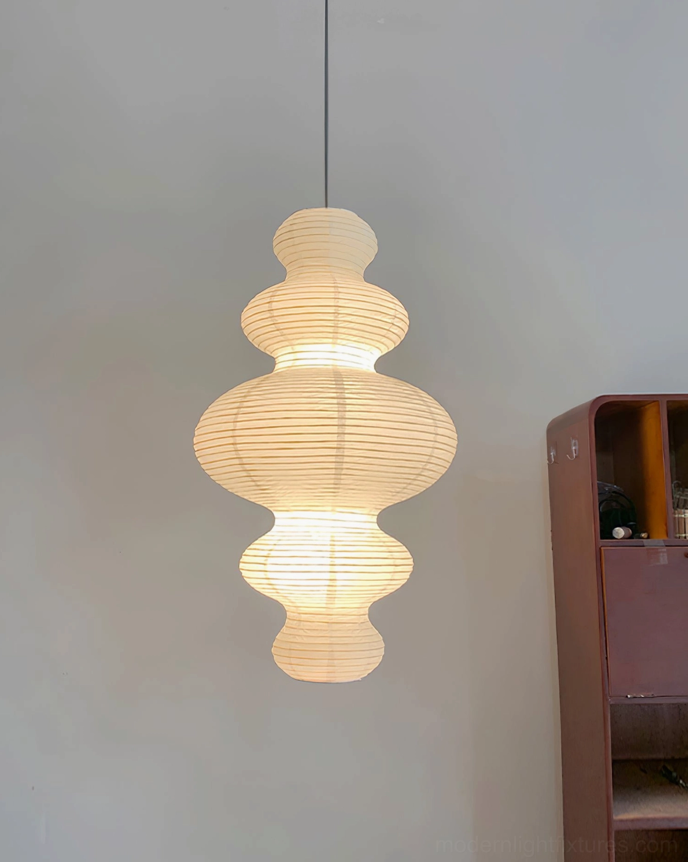 Juni plug-in pendant lamp lit above wooden furniture - hand-crafted paper shade diffusing warm light