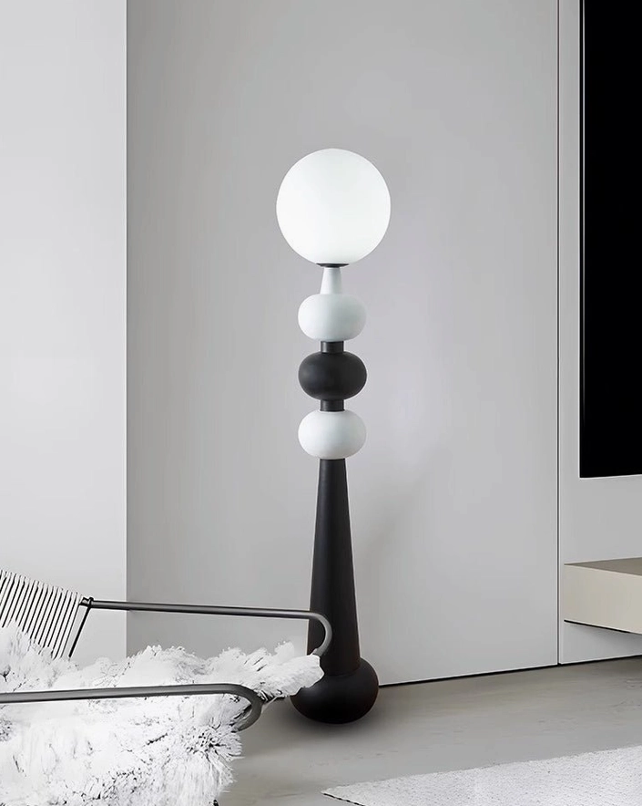 Geometric black and white stacked sphere floor lamp beside modern fur chair in minimalist living room setting