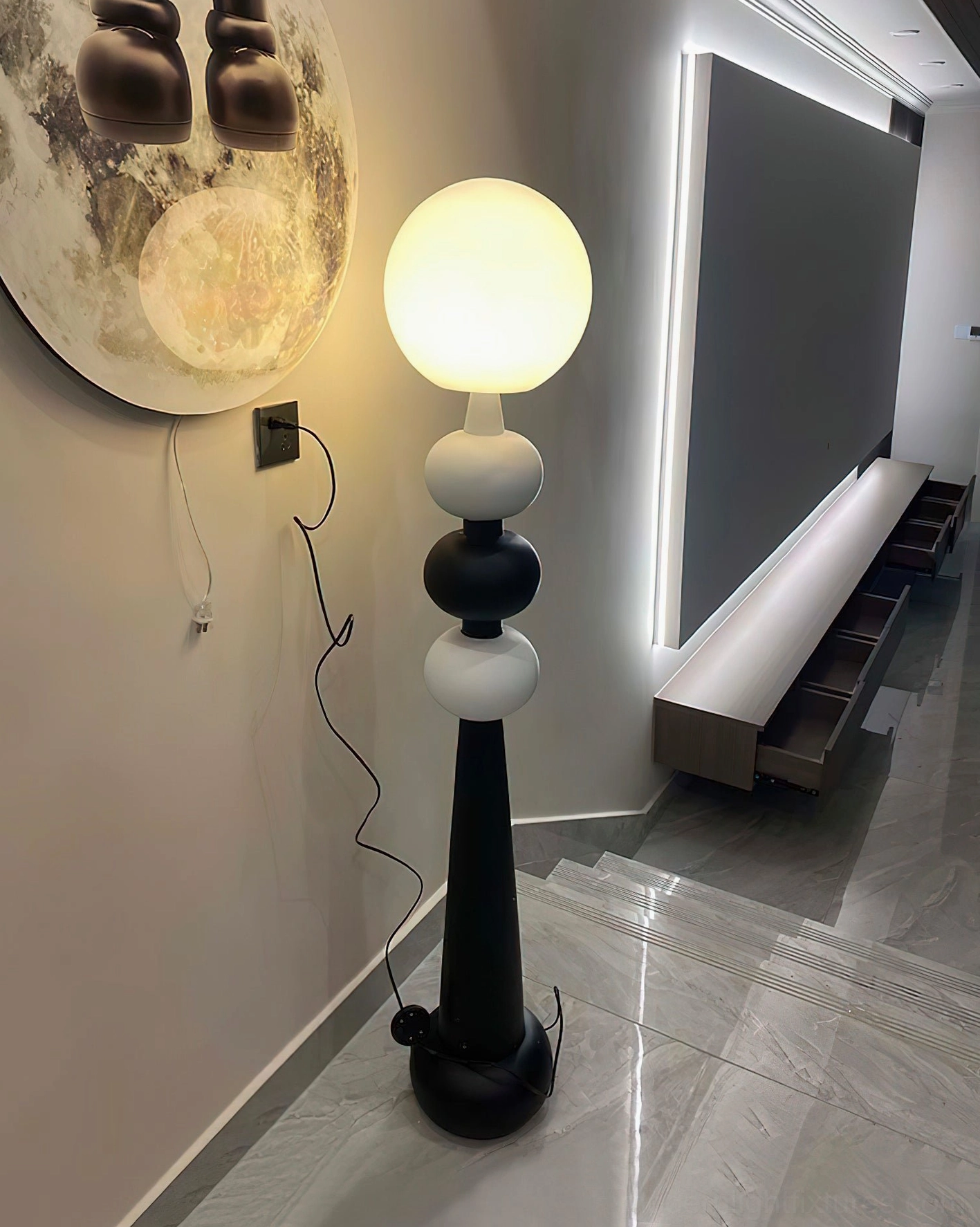 Contemporary floor lamp with geometric sphere stacking in hallway with moon wall decoration and exposed power cord