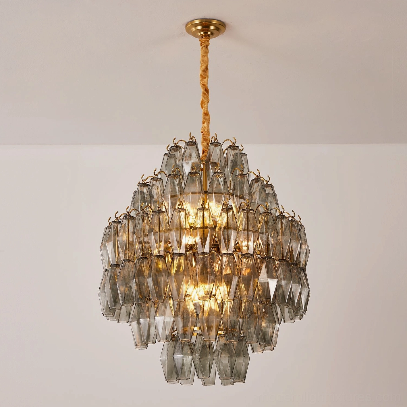 Kaelis tiered chandelier suspended overhead, showing full geometric glass prism composition and light refraction