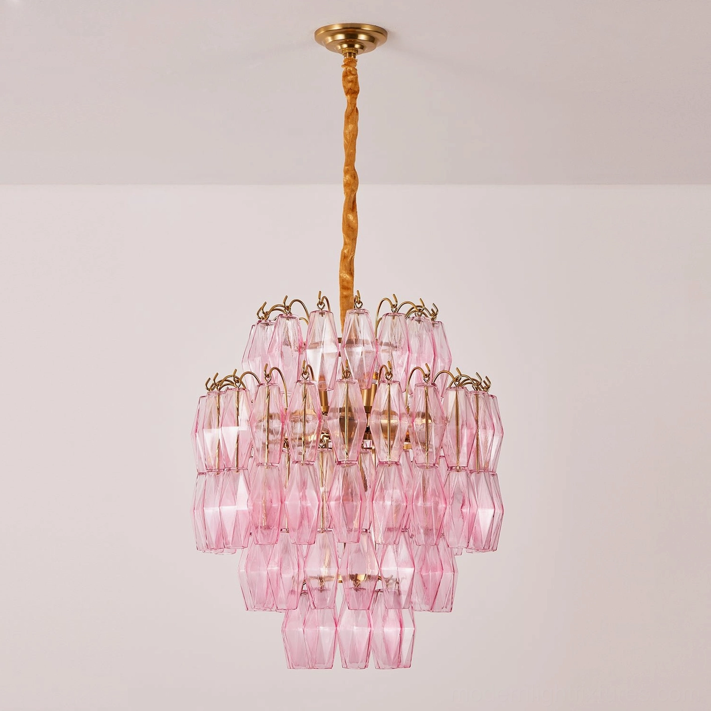 Blush pink tiered glass chandelier in interior space, side profile view of geometric faceted design