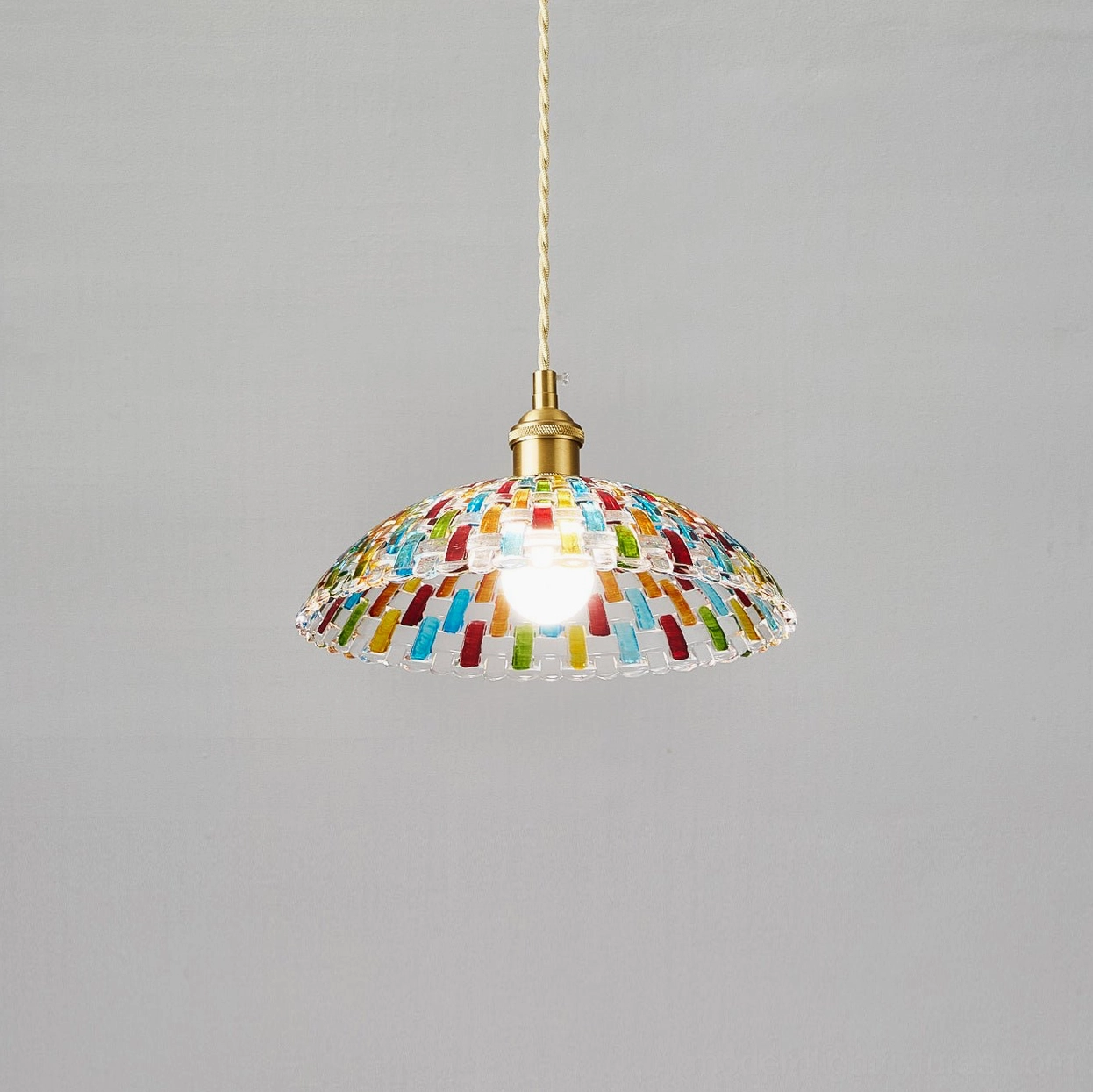 Kaleido stained glass pendant lamp three-quarter view showing exposed E26 E27 bulb, colorful glass mosaic dome shade with brass hardware