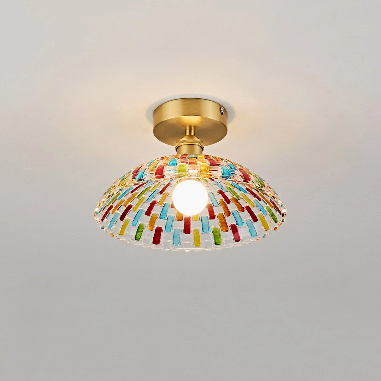 Kaleido mosaic glass ceiling light fixture overhead view with exposed lit bulb, brass canopy, multicolored hand-cut glass dome