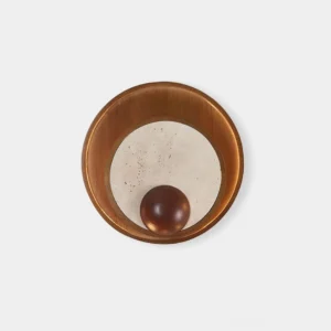 Kaplan travertine and wood wall sconce with circular design, front studio view showcasing texture and warm minimalist aesthetic