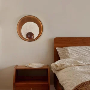 Kaplan minimalist wall sconce installed in warm bedroom interior, creating ambient light above wooden furniture