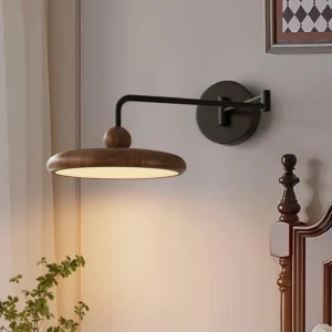 Karlin adjustable wall sconce mounted in bedroom bedside position with warm lighting over bed frame and green plant styling