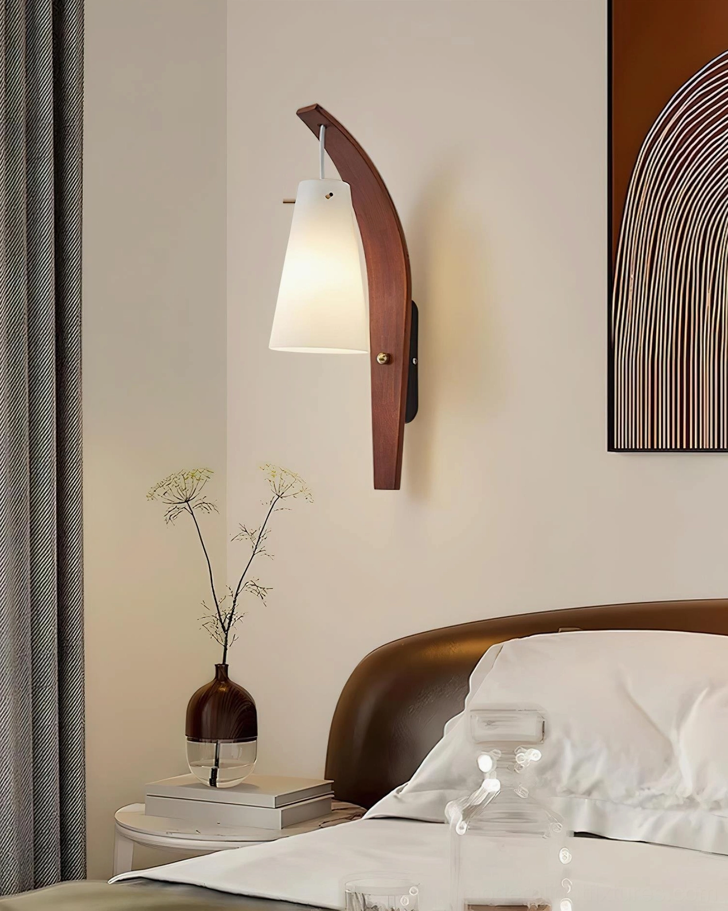 Karo wall sconce providing warm bedside illumination above nightstand with bed linens and table decor