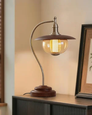 Keeper table lamp displayed on bedroom nightstand with framed wall art and decorative accessories, warm amber light ambiance