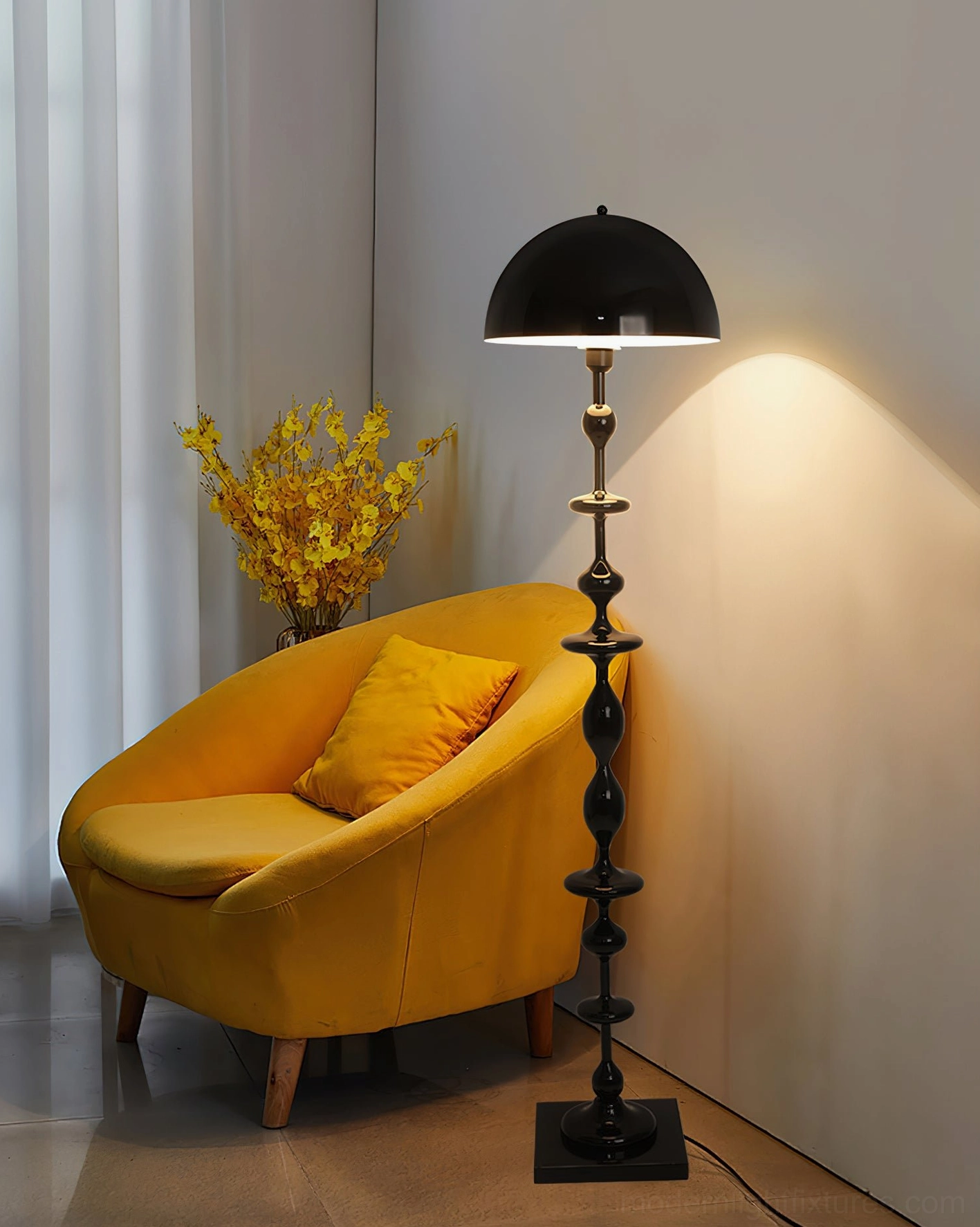Matte black Keira floor lamp with warm glowing dome creating cozy reading nook atmosphere with yellow armchair
