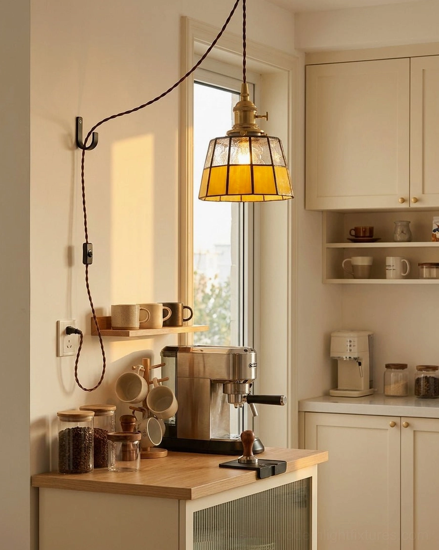 Plug-in stained glass pendant fixture hung over white kitchen cabinet with natural window light and coffee station warmth