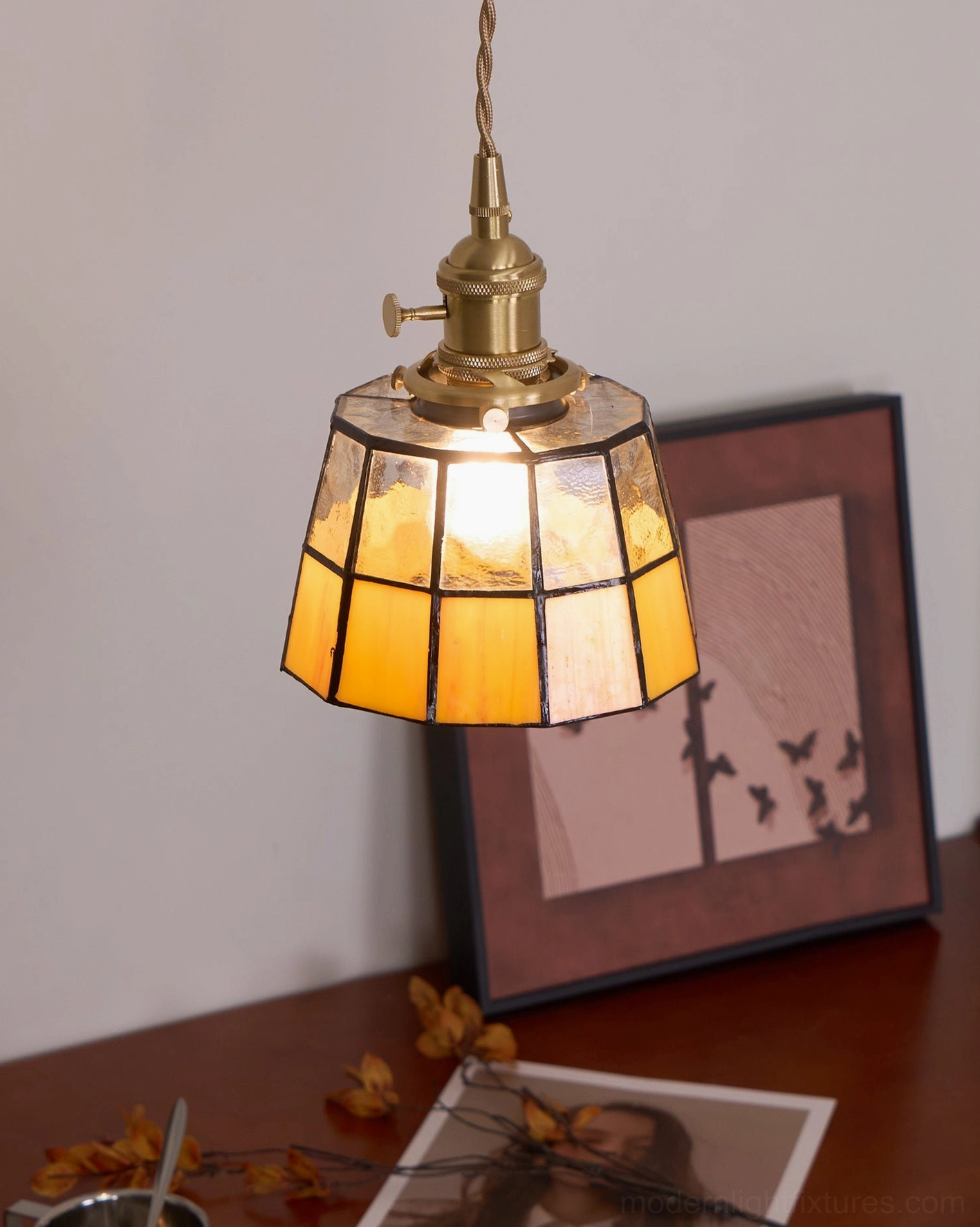 Keito handcrafted pendant light showing lit stained glass shade with black grid trim detail