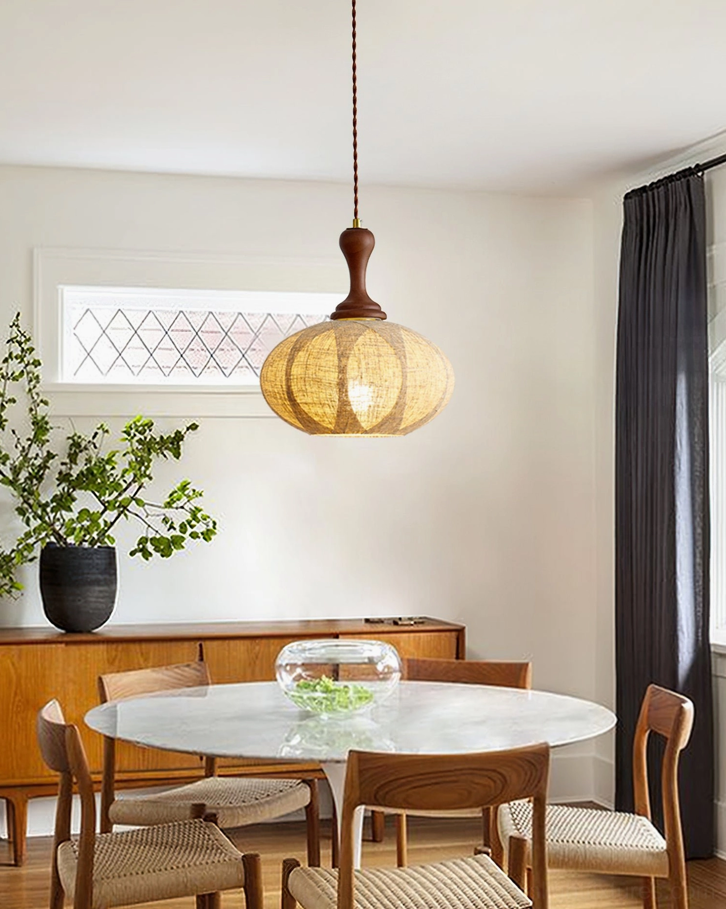 Modern fabric pendant light above wooden dining table in contemporary dining room, warm illumination