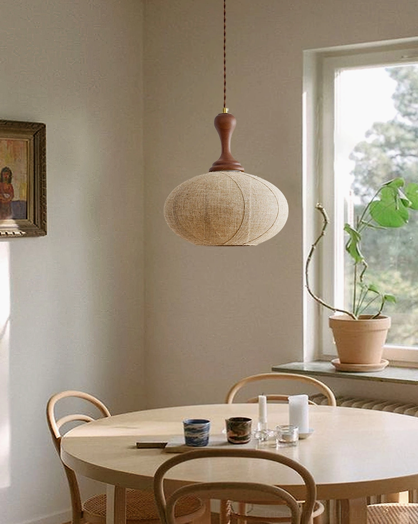 Unlit linen pendant light side view near window in residential dining room with potted plant