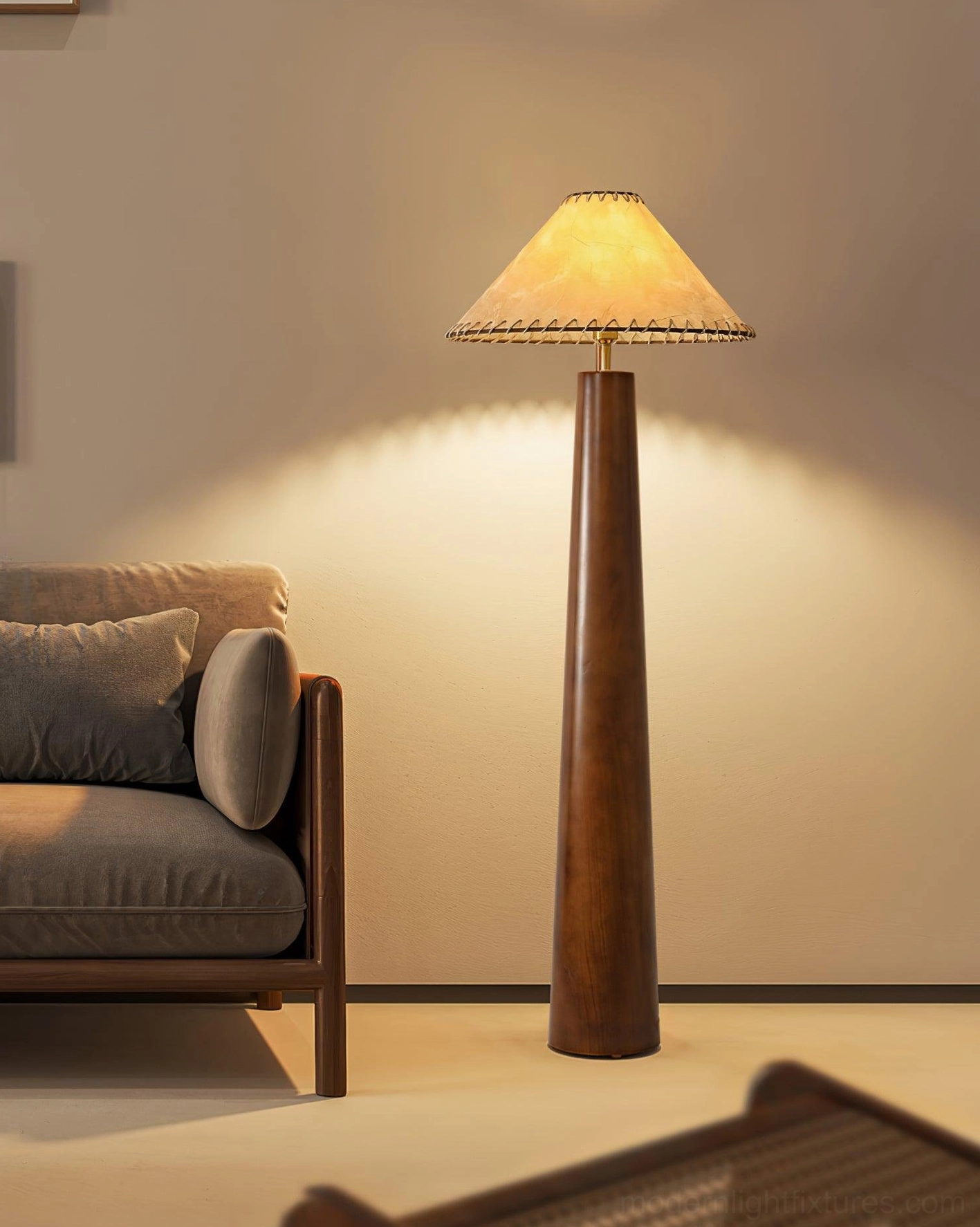 Kibo floor lamp with hand-knotted jute shade in living room with leather sofa, projecting warm ambient light