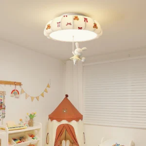 Indoor children's bedroom ceiling light fixture mounted overhead, showing warm ambient lighting from pumpkin shade with hanging rabbit plush toy decor