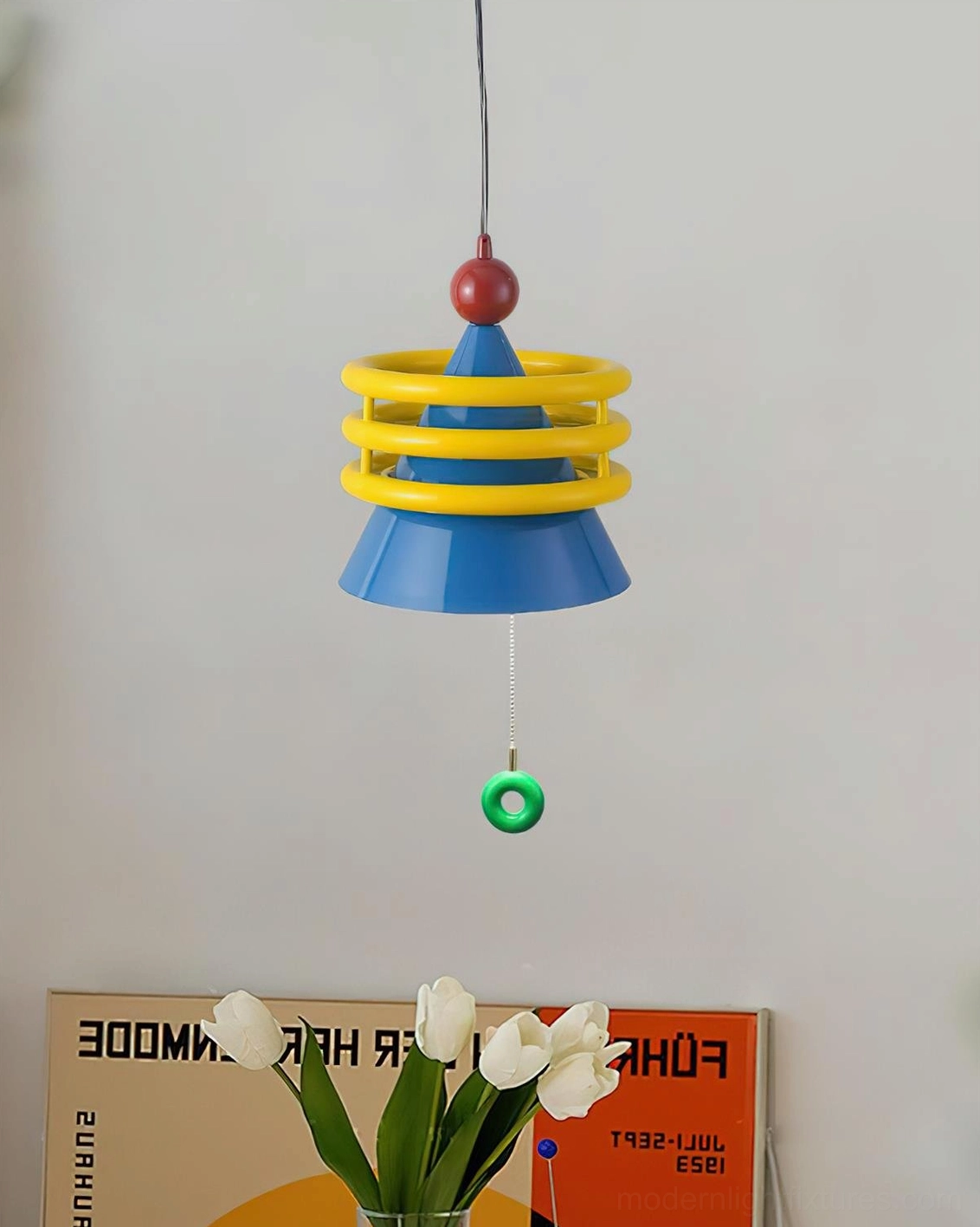 Kinetica playful geometric pendant light with blue cone shade and yellow coil accents in home decor corner with flower artwork