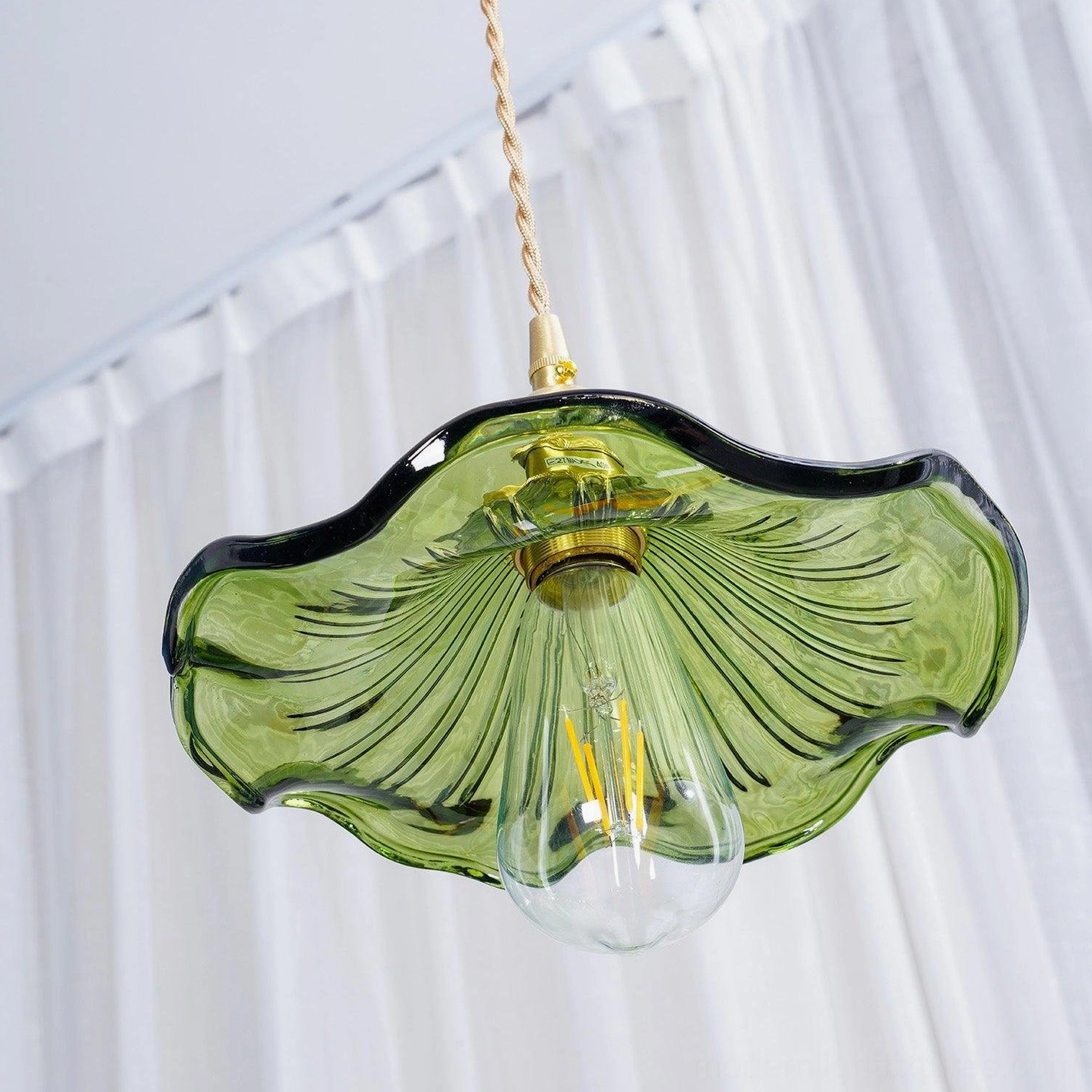 Kinney fluted glass pendant light with beige twisted cord and brass hardware hanging against sheer white curtain